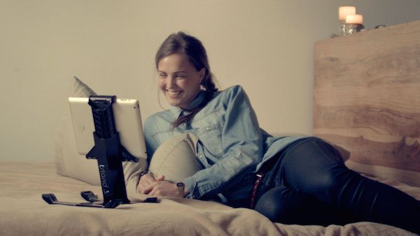 Woman reclining on bed Skyping with tstand in desktop mode